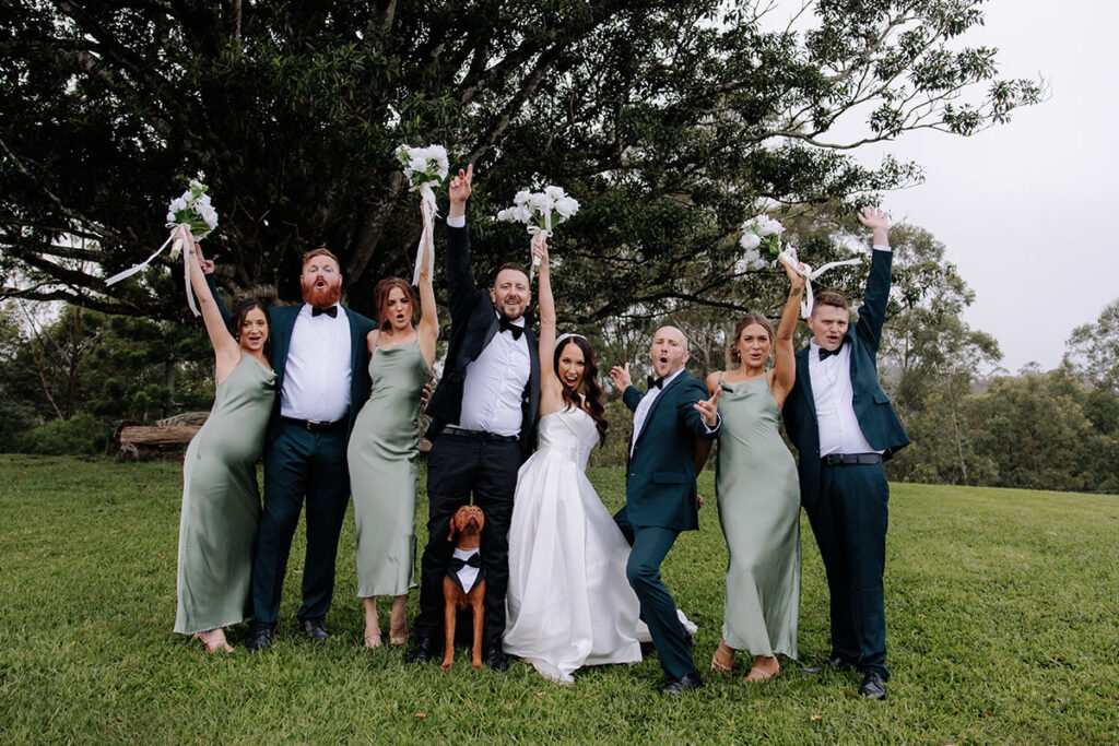 Bridal party with dog posing with boquets in front of the Fig Tree at Midginbil Eco Resort | credit: Pippi and Palm for Ash and Alex