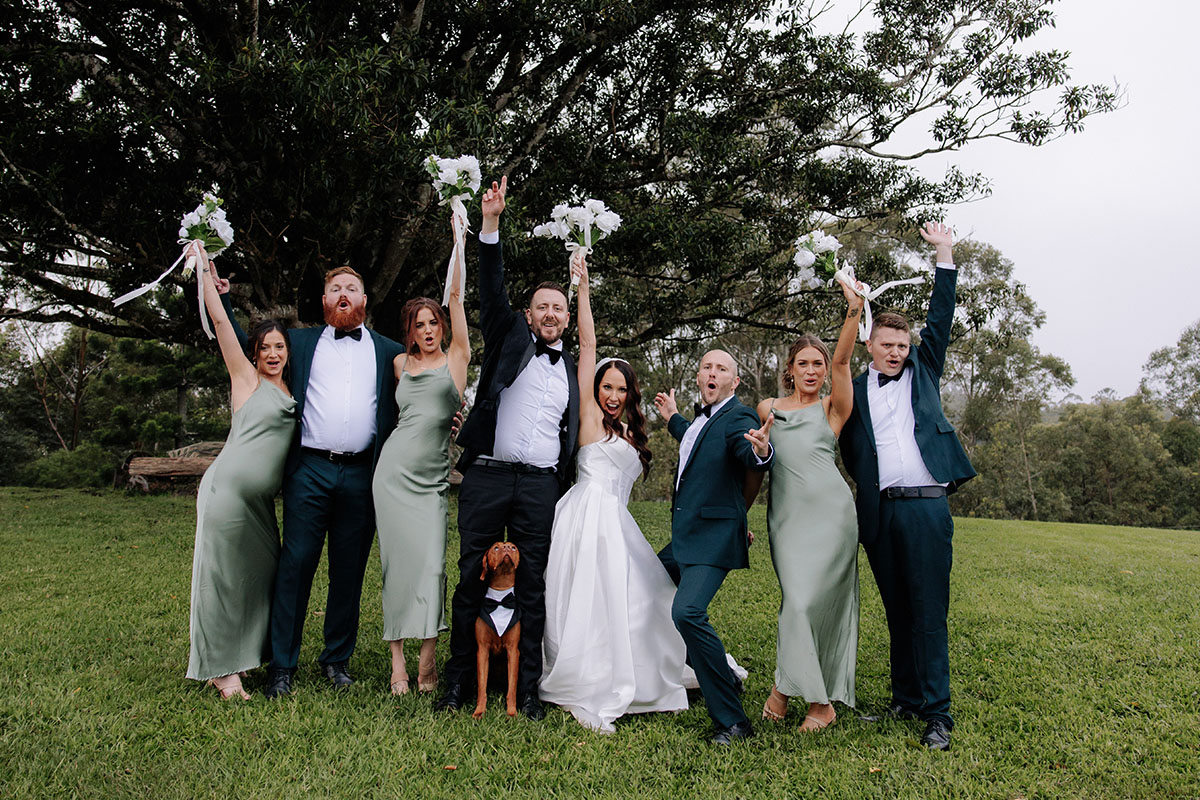 Bridal party with dog posing with boquets in front of the Fig Tree at Midginbil Eco Resort | credit: Pippi and Palm for Ash and Alex