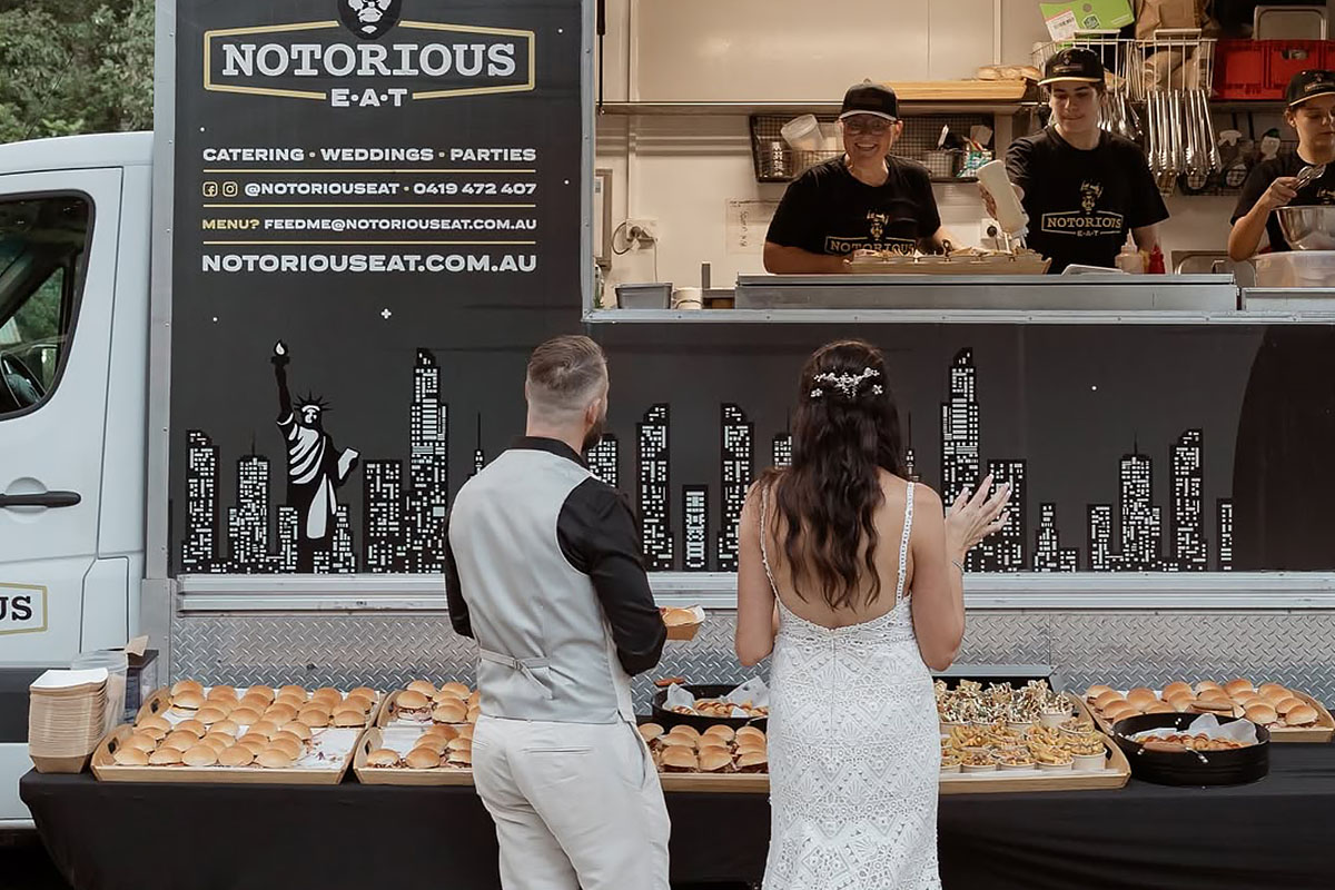 Bride and groom standing in front of food trucks at Midginbil Eco Resort