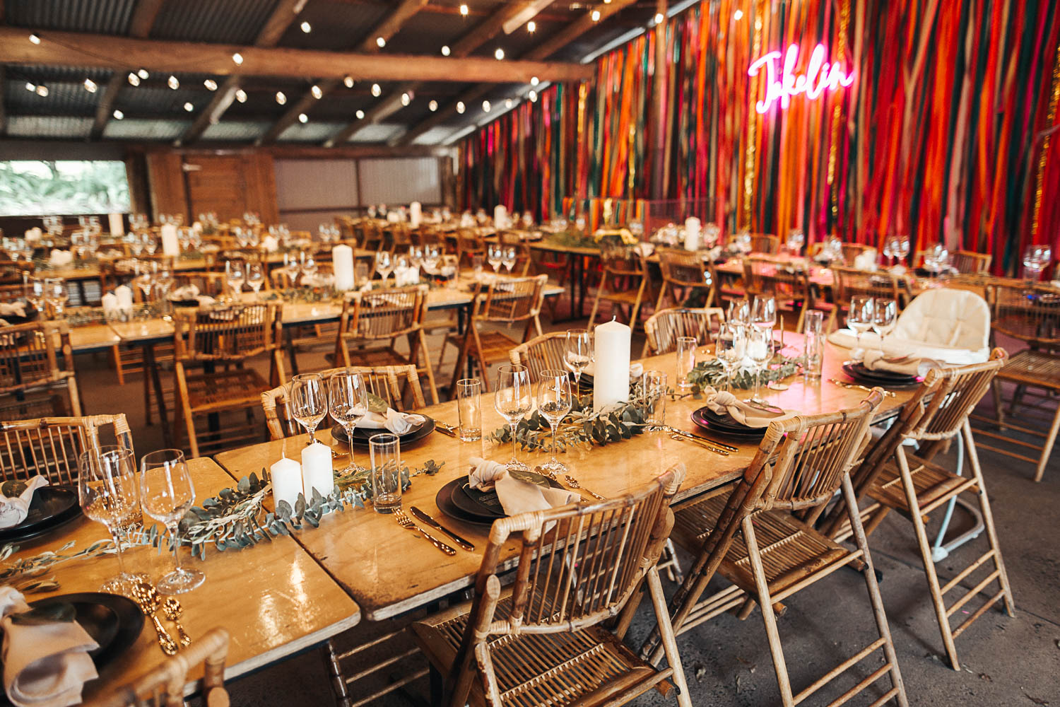 Boho styled barn wedding reception with neon script lighting, cane chairs and fairy lights